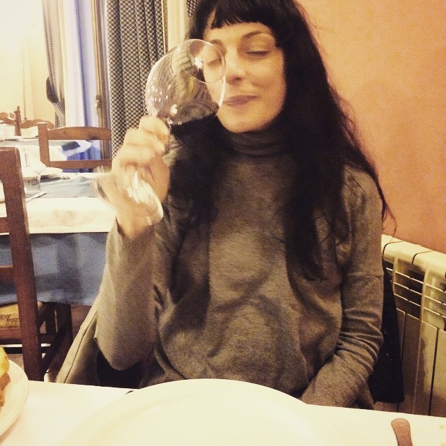 Roser Amills, con jersey gris de cuello alto y flequillo, huele una copa de vino tinto con los ojos cerrados