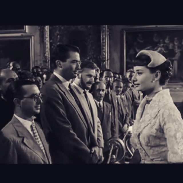 Fotograma de Vacaciones en Roma: Audrey Hepburn saluda a los periodistas, entre ellos Gregory Peck