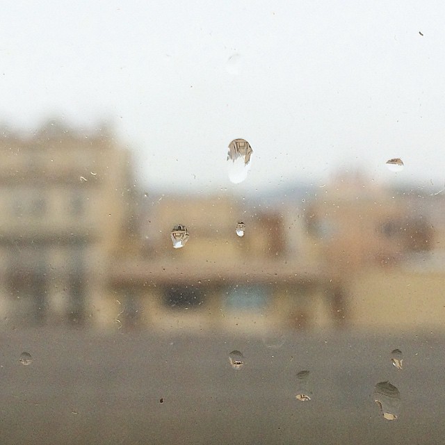Gotas de lluvia en un cristal con edificios desenfocados al fondo