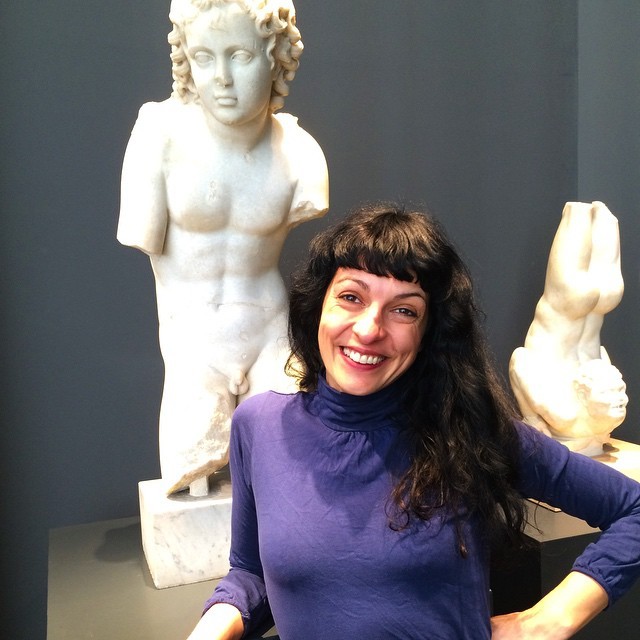 Roser Amills sonriente junto a una estatua clásica de Eros en un museo de Roma
