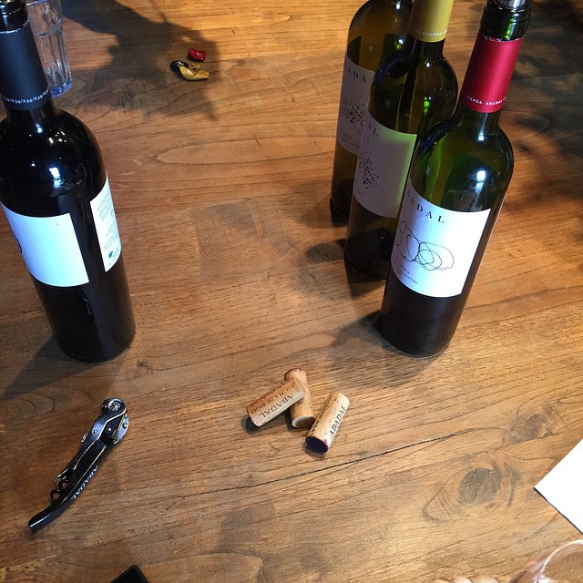 Botellas de vino abiertas y tapones sobre una mesa de madera