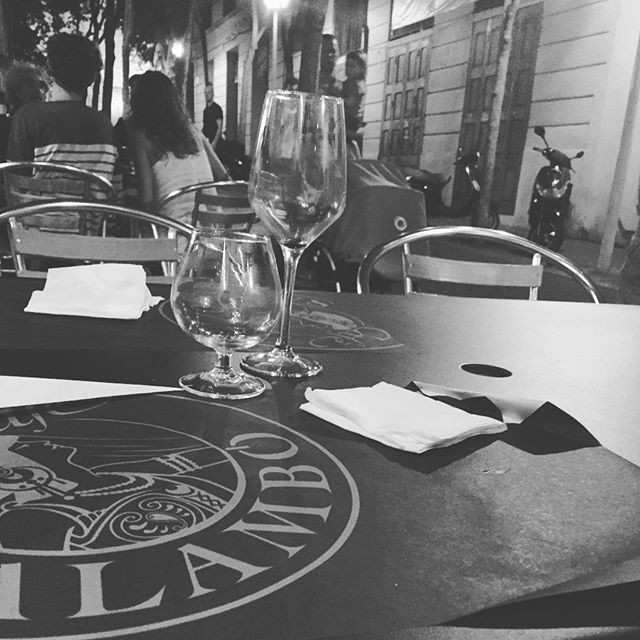 Mesa de terraza de noche, con copas vacías y servilletas sobre un mantel de papel oscuro con un logotipo
