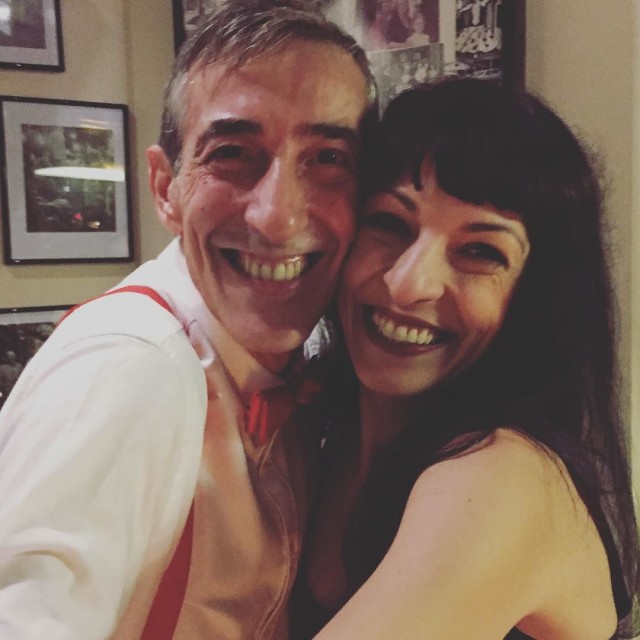 Roser Amills abrazada y sonriendo con Jorge, un hombre de camisa blanca y tirantes rojos, en Entrepanes Díaz