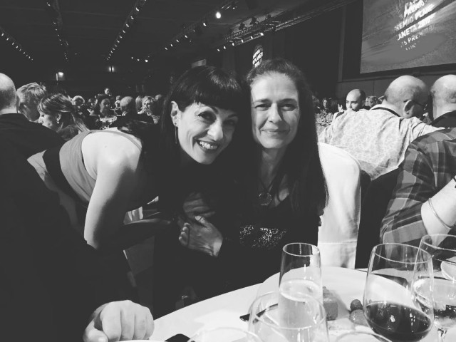 Foto en blanco y negro de Roser Amills abrazada a Anika Entre Libros en una mesa de la gala del Premio Planeta