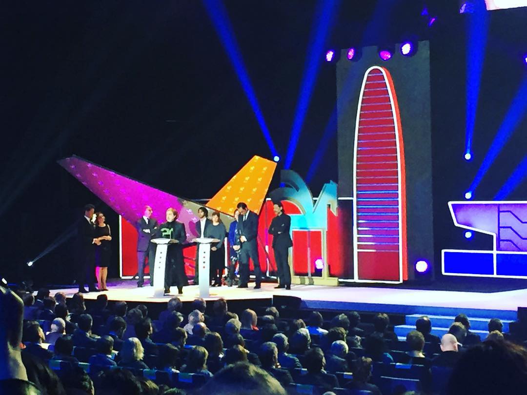 Premiados sobre el escenario de la gala de los Premios Ondas 2015, junto a dos atriles, con el decorado de la ciudad al fondo