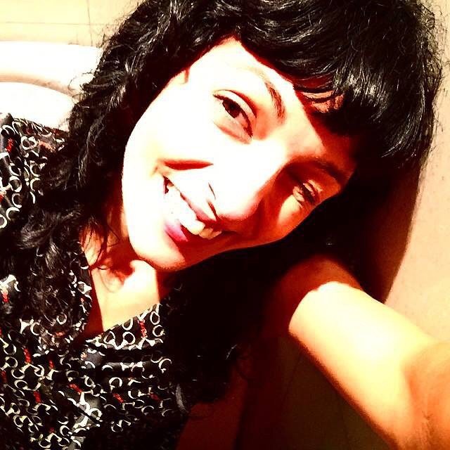 Autorretrato de Roser Amills sonriendo, con el rostro iluminado por el sol y camisa de estampado geométrico