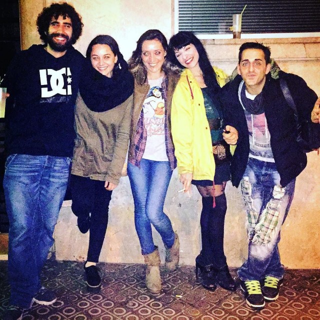 Cinco amigos posan apoyados en una pared en la calle de noche; Roser Amills, con impermeable amarillo, junto a Marc Alberola, Laura, Pistatxito y Samu
