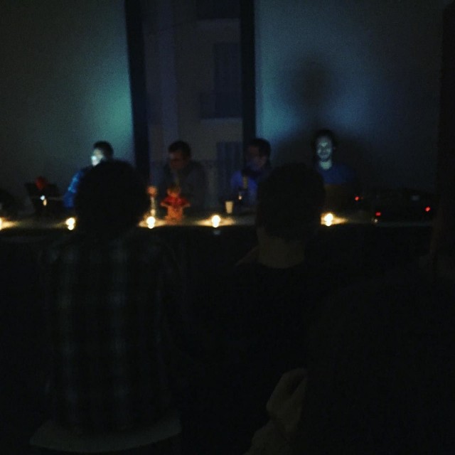 Programa de radio en directo a oscuras: el público en penumbra frente a la mesa de los locutores, iluminada con velas