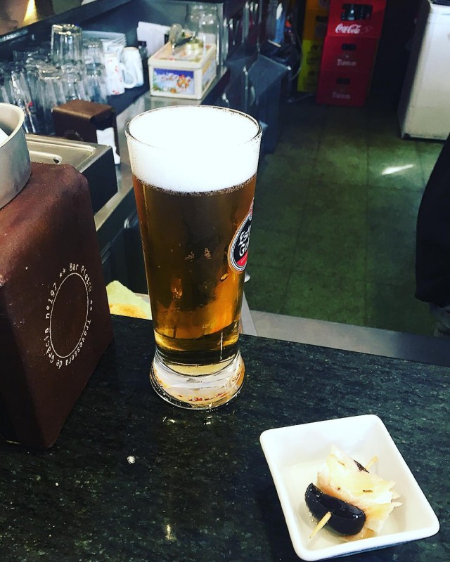 Caña de cerveza y un platillo con aceitunas sobre la barra de un bar