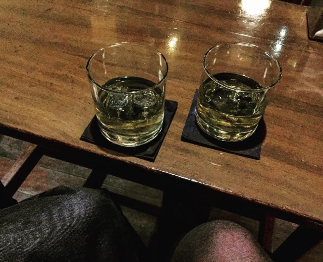 Dos vasos con hielo y una bebida clara sobre una mesa de madera