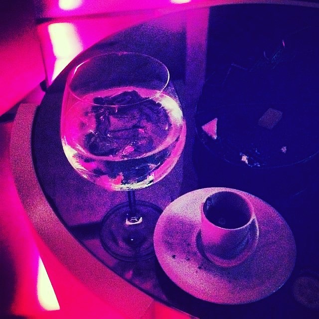 Copa con hielo y una tacita sobre una mesa iluminada con luz violeta