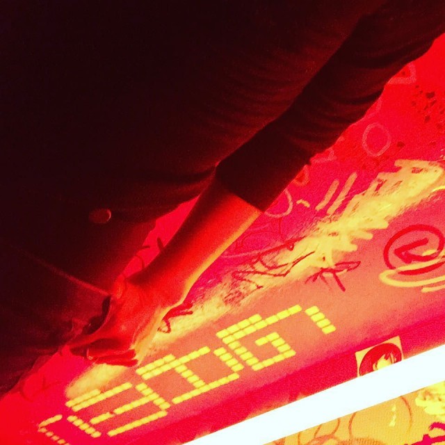 Mano apoyada sobre una pared roja cubierta de pintadas y letras