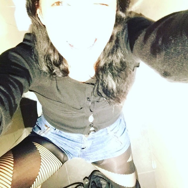Persona sentada, fotografiada desde arriba, con jersey negro, shorts vaqueros y medias de rejilla