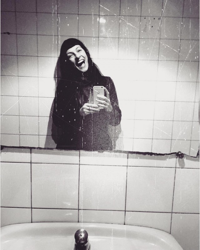 Autorretrato en blanco y negro ante un lavabo y una pared de azulejos blancos
