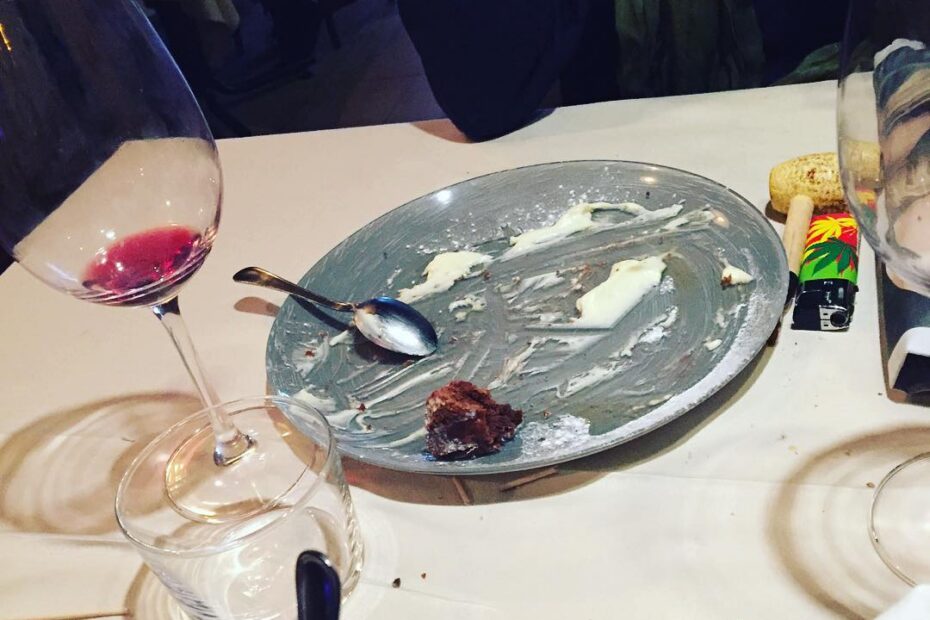 Mesa de restaurante tras la comida, con una copa de vino tinto y un plato casi vacío