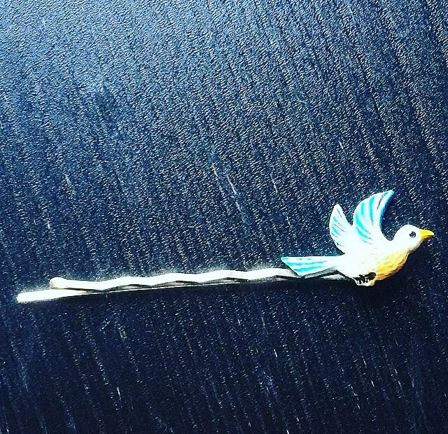 Horquilla para el pelo con un pajarito azul y amarillo sobre una tela vaquera