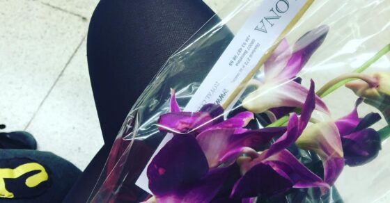 Orquídea morada envuelta en celofán sobre las rodillas de Roser Amills