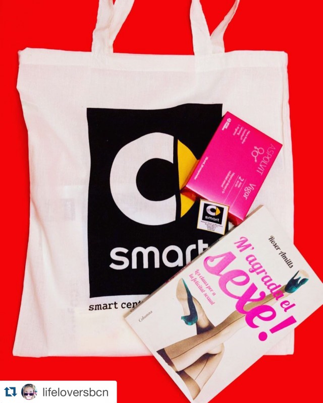 Bolsa blanca de tela de Smart Center con una caja rosa de Aspolvit y el libro M'agrada el sexe! de Roser Amills sobre fondo rojo