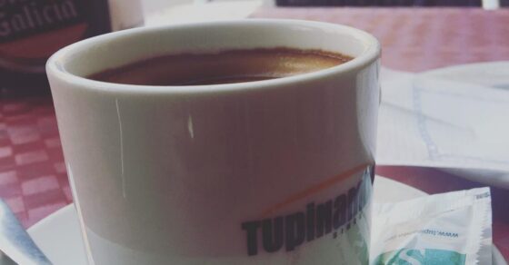 Taza de café solo sobre una mesa de terraza, con un sobre de azúcar, en el barrio de Gràcia