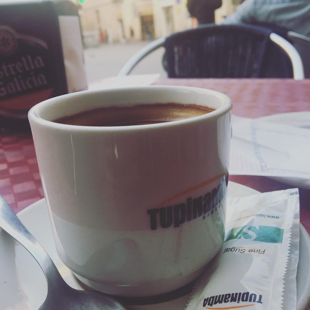 Taza de café solo sobre una mesa de terraza, con un sobre de azúcar, en el barrio de Gràcia