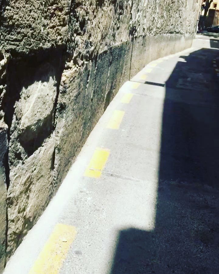 Muro de piedra y acera con líneas amarillas en una calle de Palma