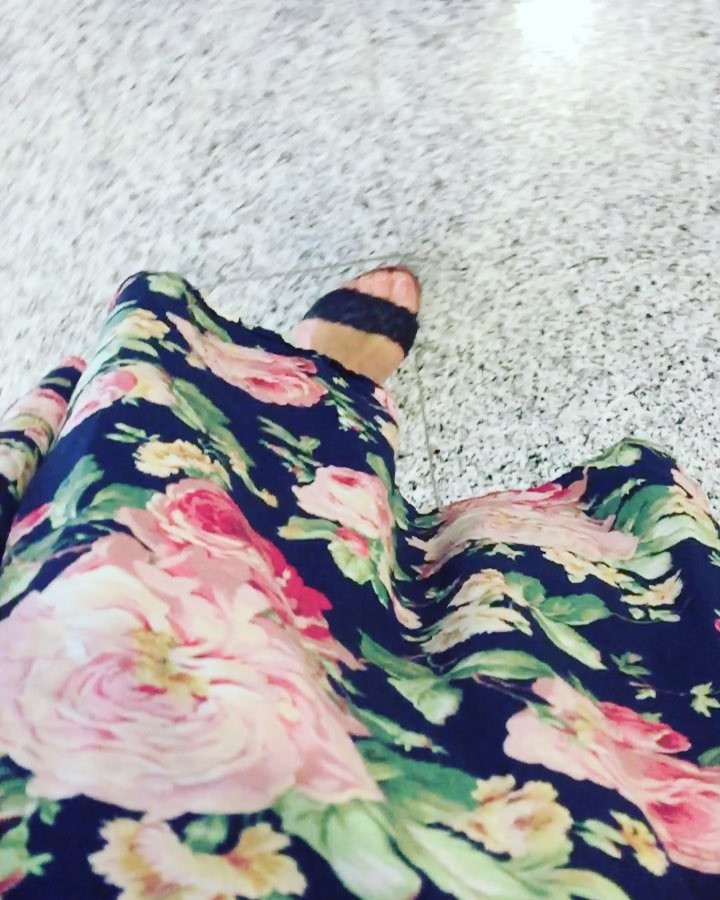 Falda de flores rosas sobre fondo azul marino y un pie con sandalia sobre un suelo de terrazo