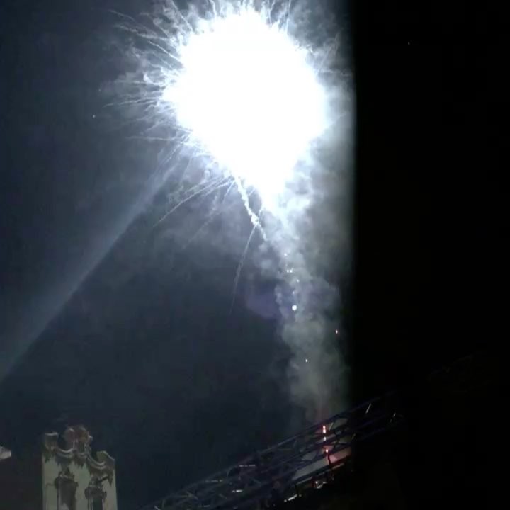 Un esclat de focs artificials blancs al cel negre, sobre les teulades
