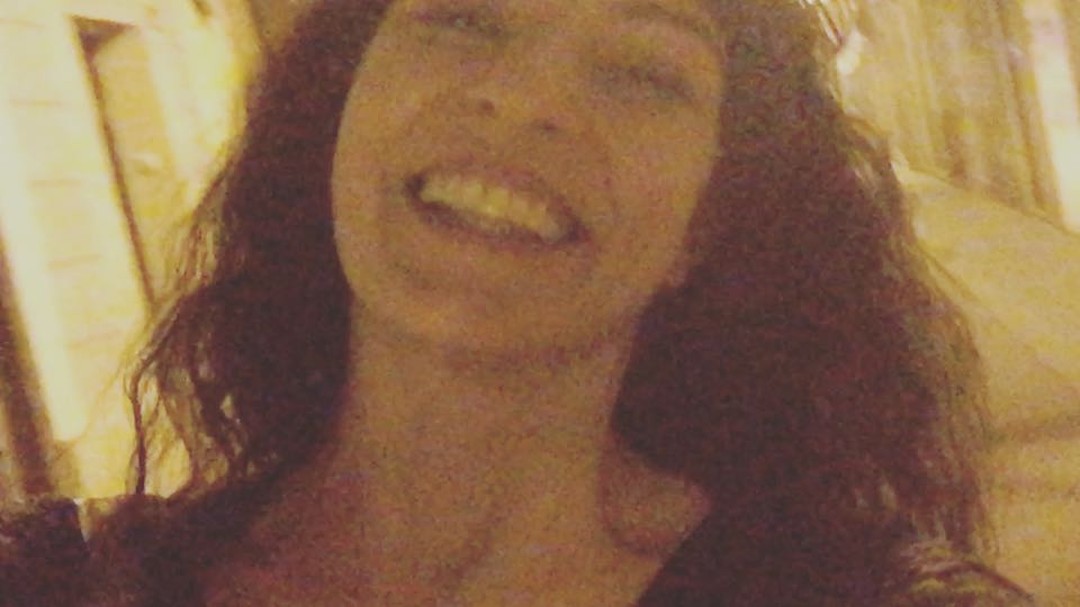 Selfi nocturno de Roser Amills riendo, con el pelo rizado, bajo la luz anaranjada de una calle