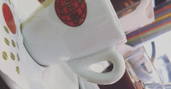 Una taza de café blanca con un sello rojo, vista de cerca sobre su plato