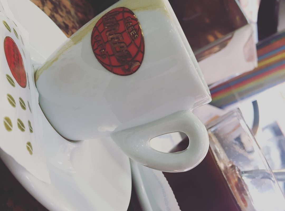 Una taza de café blanca con un sello rojo, vista de cerca sobre su plato