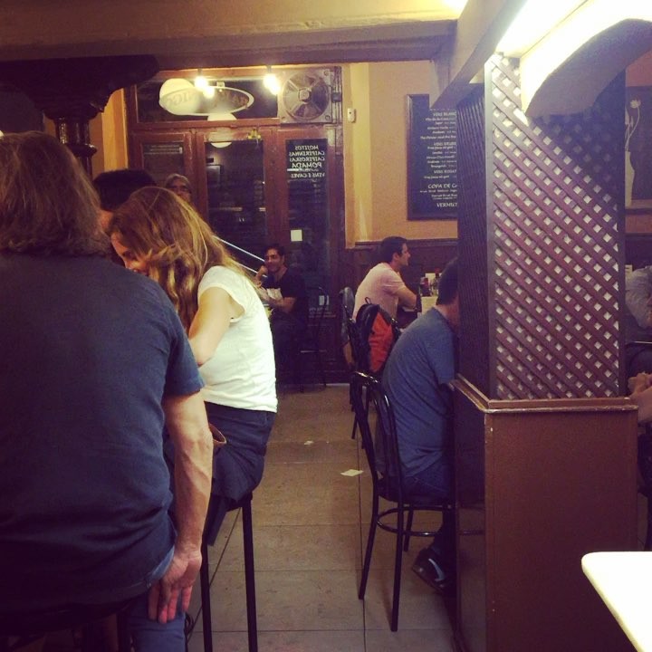 Interior del bar Canigó de Gràcia, con gente en la barra y en las mesas altas