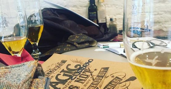 Mesa con copas de cerveza, una libreta de cubierta kraft con letras decorativas y bolsos, durante una clase de redes sociales