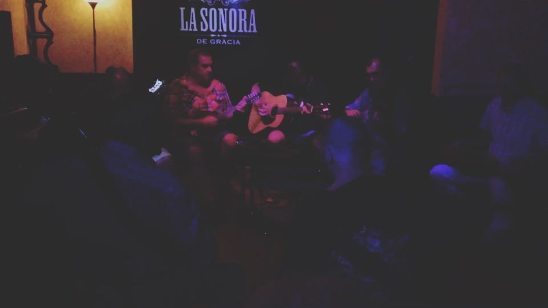 Escenario en penumbra de La Sonora de Gràcia, con músicos tocando bajo una luz azulada