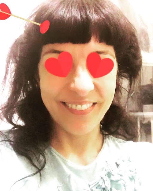 Mujer sonriente con el pelo despeinado y dos corazones rojos sobre los ojos, filtro de Instagram