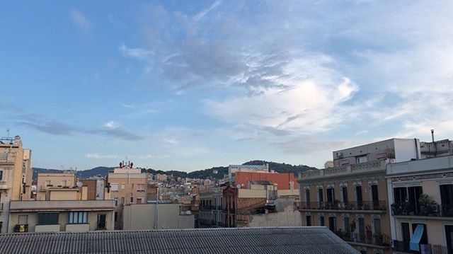Cielo con nubes sobre los tejados de una ciudad, con colinas al fondo