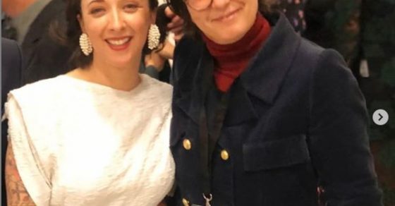 Bea Castelló junto a otra mujer, con acreditación, en un acto con público