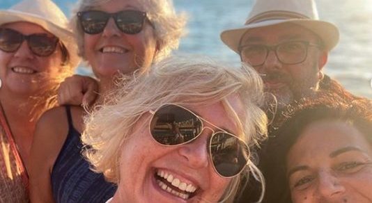 Selfi de Carmen Linares con varias amigas y un amigo, con gafas de sol, al atardecer junto al mar