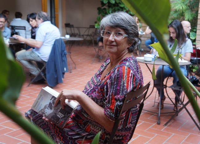 Conxita Guixà sentada en la terraza de un café, con un libro en las manos