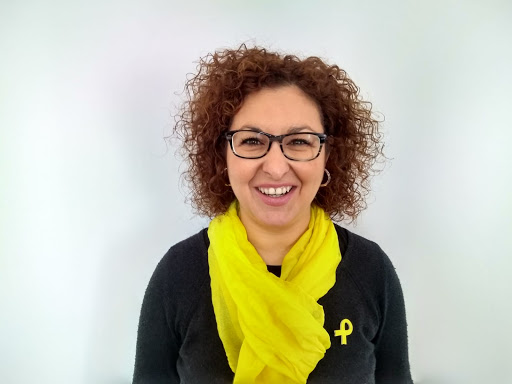 Retrato de Ainoa Olza, con gafas, pelo rizado y fular amarillo