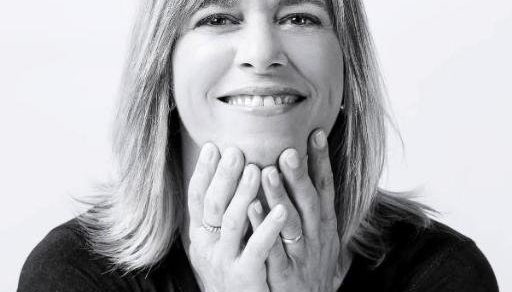 Retrato en blanco y negro de Ana Cuatrecasas sonriendo, con la cara apoyada en las manos