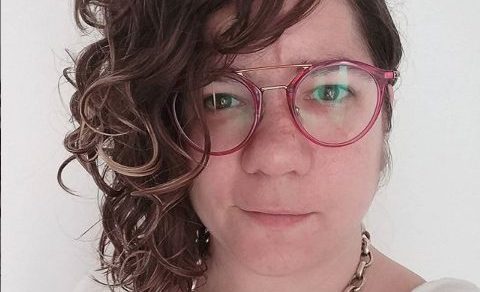 Retrato de Anna Amat con gafas rosas y pelo rizado