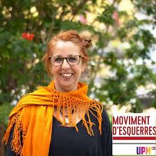 Anna Llusent, con gafas y fular naranja, ante un cartel del Moviment d'Esquerres