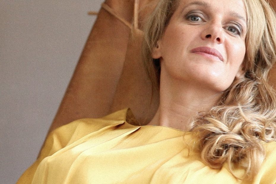 Claire Davies, con blusa amarilla, recostada en una butaca