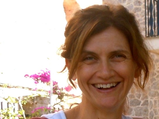 Retrato de la novelista Mar Mella sonriente al aire libre, con buganvillas al fondo