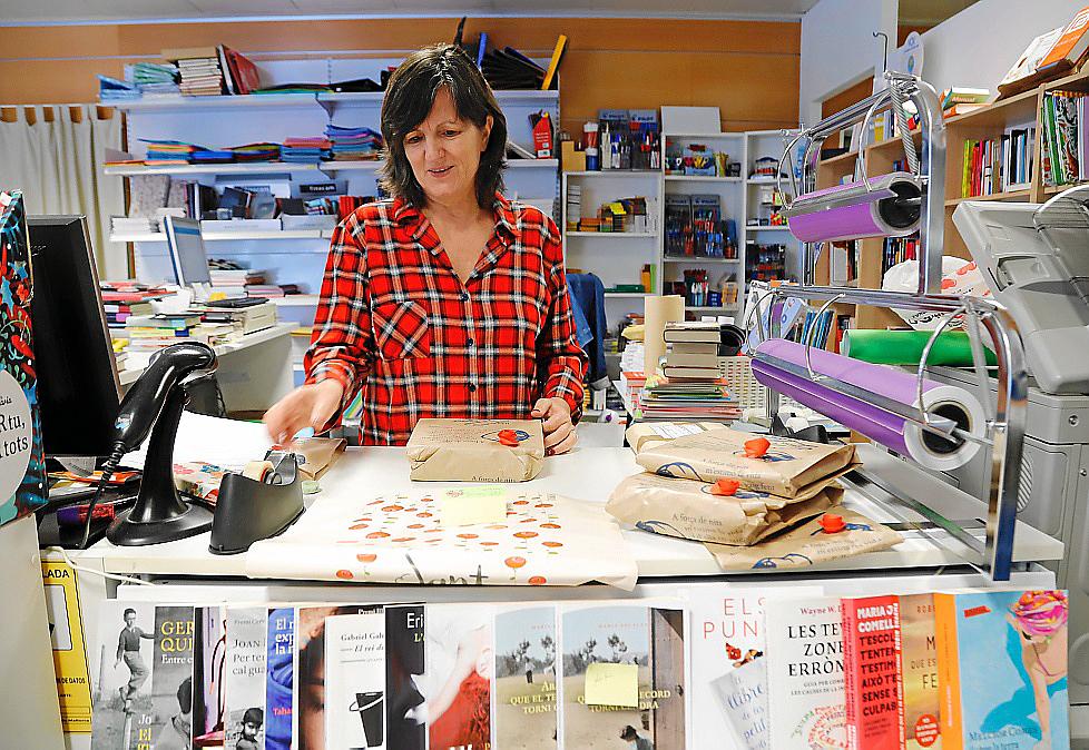 Maria Barceló envuelve libros tras el mostrador de la Llibreria Lluna de Palma