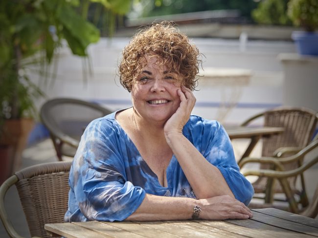 Retrato de la poeta Marta Pérez Sierra sentada a una mesa de terraza