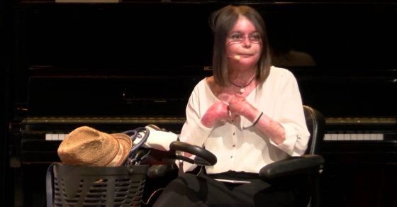 La escritora Nina Roma en un escenario, junto a un piano