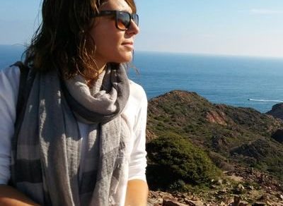 Olga Samper, con gafas de sol y fular, mira al mar desde un acantilado