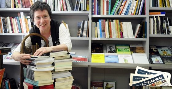Rosa Cubeles sonriente entre pilas de libros en su librería