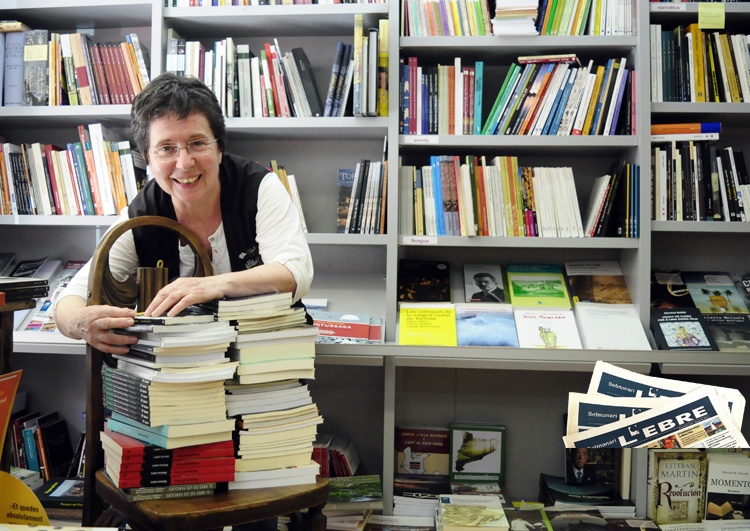 Rosa Cubeles sonriente entre pilas de libros en su librería